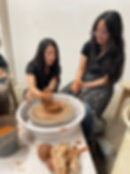 two women playing with clay on the ceramic wheel