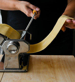 Woman using a pasta machine to make handmade pasta sheets.jpg