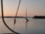 Small trawler anchored in a calm bay at sunset.