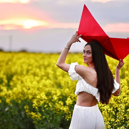 Портрет на усмихнато момиче сред цъфнало поле от рапица при залез – фотограф Елица Гунчева