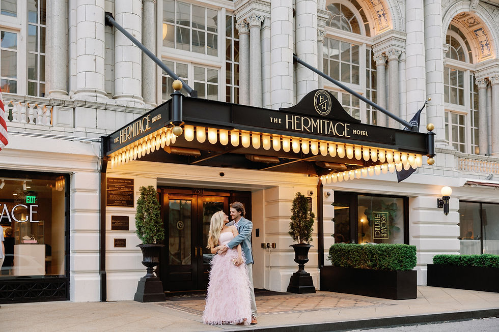 Groom in a light blue suit with his arms around his bride in a pink feather gown outside their rehearsal dinner at The Hermitage Hotel.