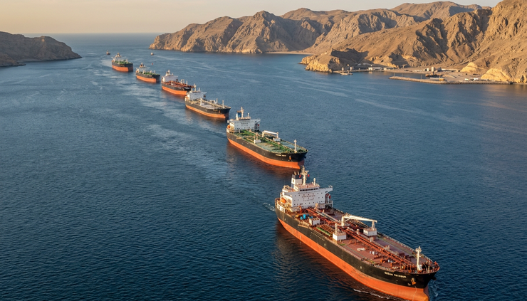 High-angle view of multiple tankers spaced across a blue sea lane