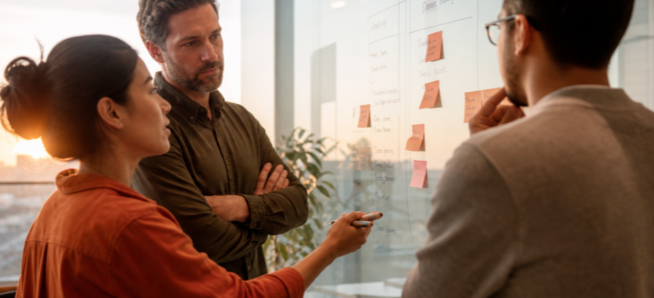 A product and engineering team at a whiteboard weighing build versus buy options for a software decision