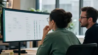 A CRM administrator reviewing a user-permission and org-hierarchy screen with a team in a modern office, teal-green tones.