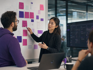A software team collaborating around a wall of sticky notes and a project board