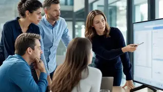 A team being trained on Zoho CRM around a monitor in a modern office