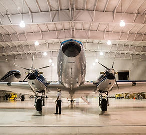 Security officer inspecting airplane inside large hangar