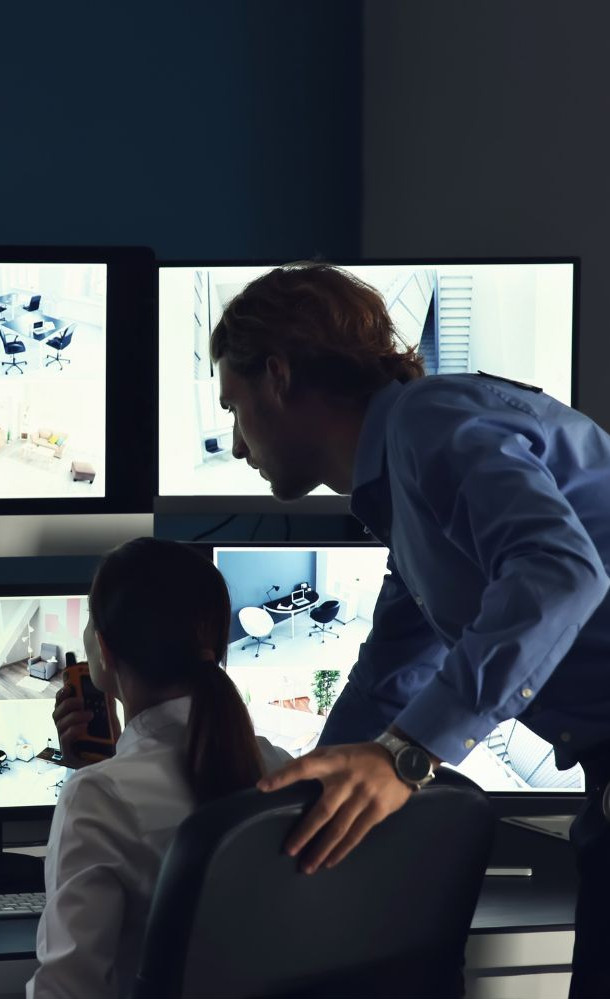 Security personnel monitoring multiple surveillance camera screens
