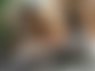 Couple sitting cross-legged on bed holding hands and talking calmly.