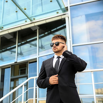Bodyguard in suit using earpiece outside modern building