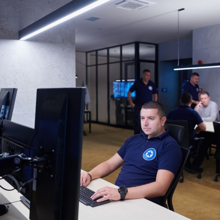 Security monitoring team overseeing surveillance cameras in a control room.