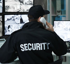 Security guard monitoring multiple CCTV screens by phone
