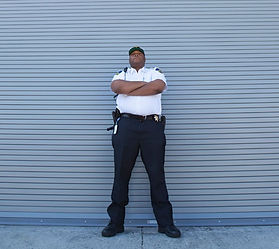 Security officer standing confidently with arms crossed outside warehouse