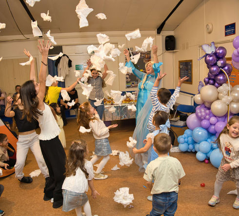 Children playing and throwing tissues in the air during a lively party with entertainer