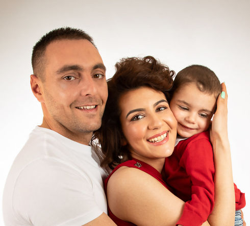 Parents hugging their child closely while smiling during studio family photoshoot