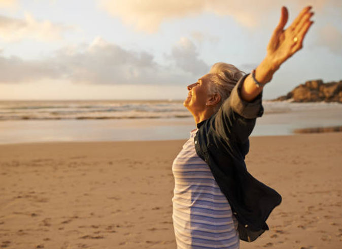 Femme sur le bord de la mer les bras ouverts