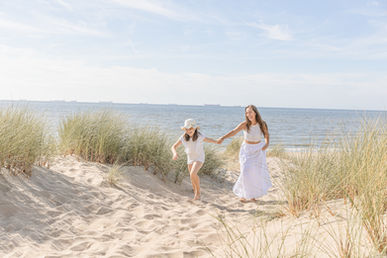 Tochter hält die Hand ihrer Mutter und führt sie durch die Natur – liebevolle Momentaufnahme von Saskia Rachor.