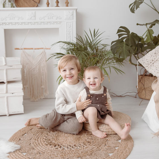 Kuschelmomente in Saskia Rachors Fotostudio in Darmstadt zeigt ein authentisches Familienfotos zweier Geschwister die auf dem Boden sitzen und lachen.