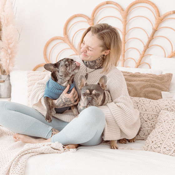 Lachende Frau mit zwei kleinen Hunden auf Bett