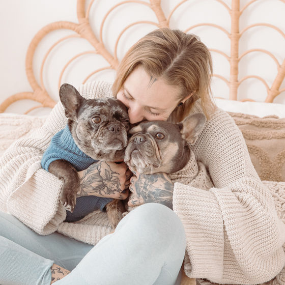 Frau kuschelt mit zwei französischen Bulldoggen.