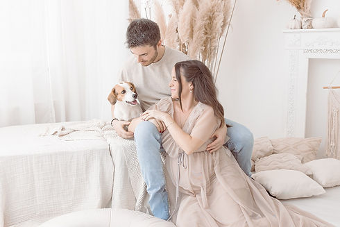 Werdende Eltern sitzen gemeinsam mit ihrem Hund in heller Boho-Kulisse auf dem Bett und genießen einen ruhigen Moment beim Babybauchshooting nahe Darmstadt.