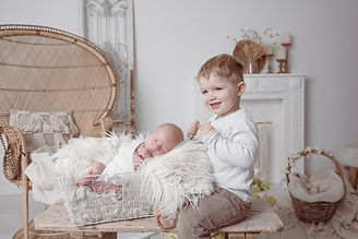 Lächelnder großer Bruder wacht über schlafendes Neugeborenes im Studio.