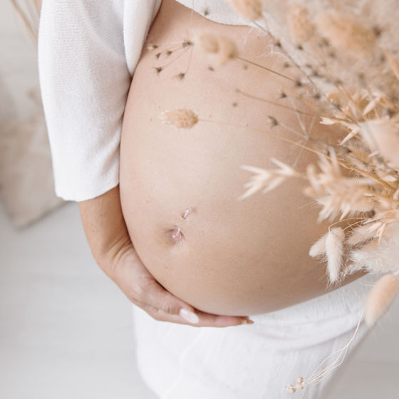 Schwangerer Bauch mit Sternchen und Trockenblumen vom Babybauch-Shooting