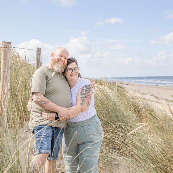 Paar umarmt sich in den Dünen am Strand.