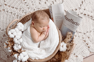 Neugeborenes in weißen Tuch eingewickelt in einem Korb bei Newborn-Fotoshooting in Darmstadt und Umgebung von Saskia Rachor