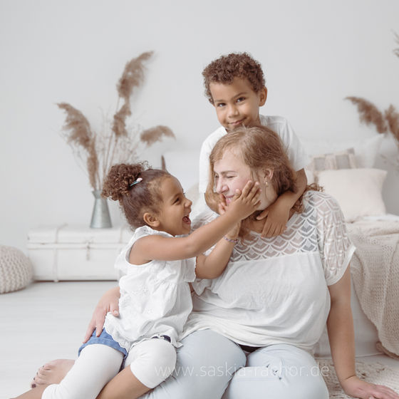 Ein emotionales Familienfoto aufgenommen in dem Fotostudio von Saskia Rachor in Darmstadt zeigt eine Familie die auf dem Boden sitzt kuschelt.