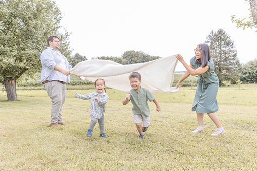 Lustiges Foto einer Familie, die ausgelassen mit einer Decke spielt und ihre zwei Kinder in der Natur bei Darmstadt Dieburg zum Lachen bringt