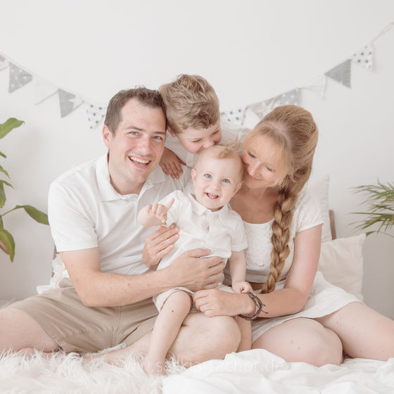 Familienfoto im schönen Fotoatelier von Saskia Rachor in Darmstadt: Eltern mit zwei Kindern kuscheln zufrieden auf einem Bett