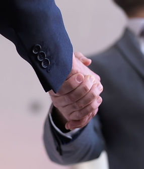Two business professionals in suits shaking hands to finalize a partnership agreement at SMSCo.