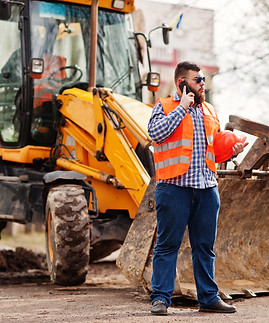 beard-worker-man-suit-construction-worker-in-safety-orange-helmet-sunglasses-against-tract