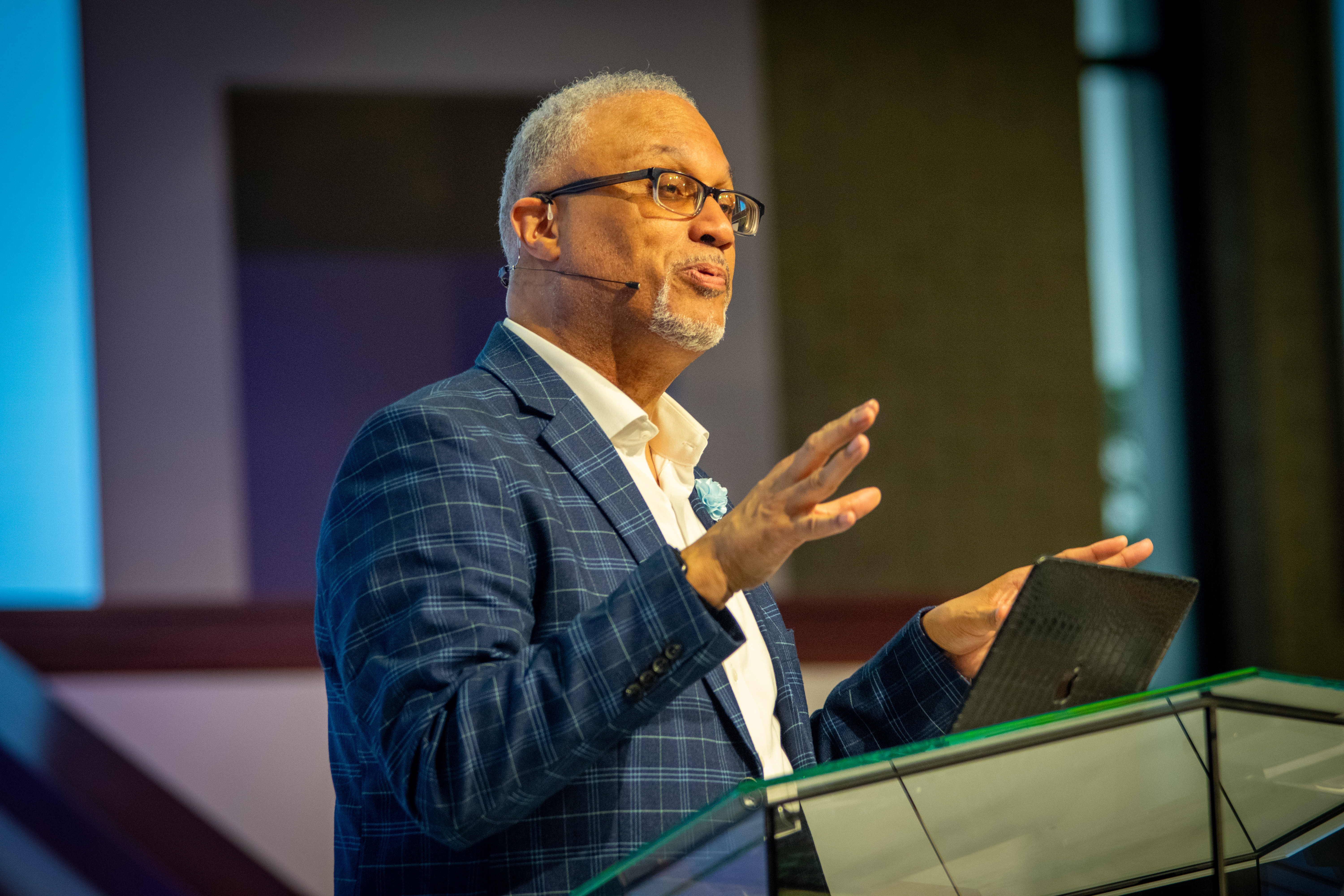 Larry Walters speaking at a lectern, gesturing to the audience at a men's gathering