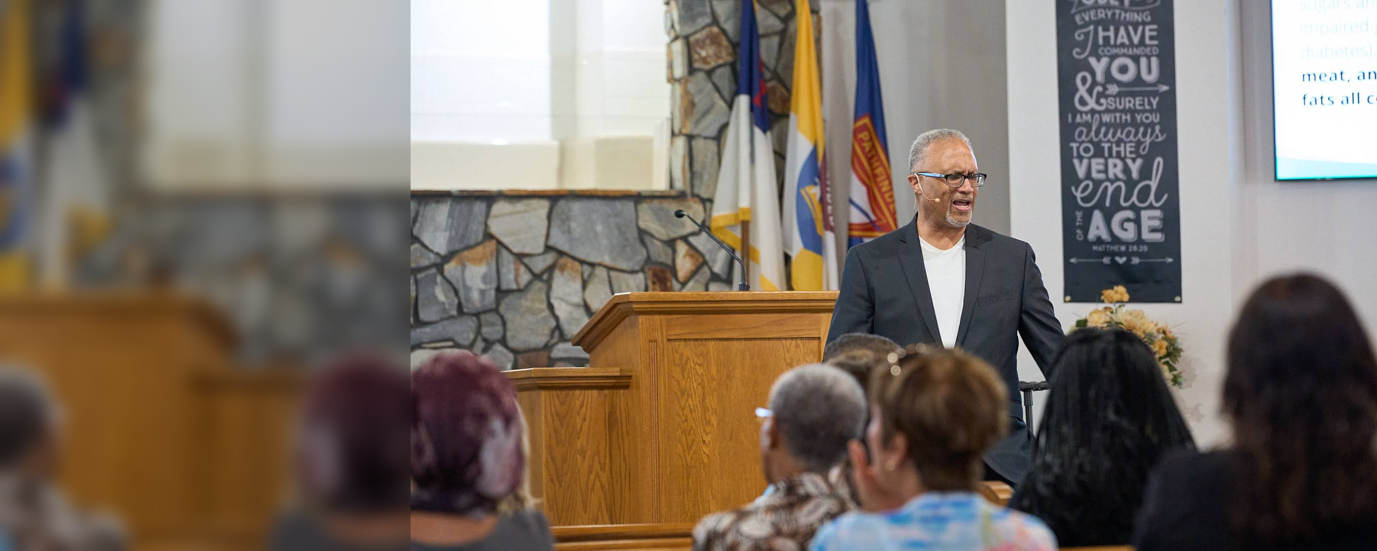 Larry Walters speaking at a church gathering with the original audience clearly visible in the foreground