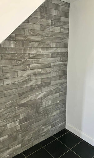 Gray textured brick wall under an angled ceiling, adjacent to a smooth white wall