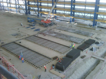 An elevated view looking down into a vast industrial construction site with yellow machinery