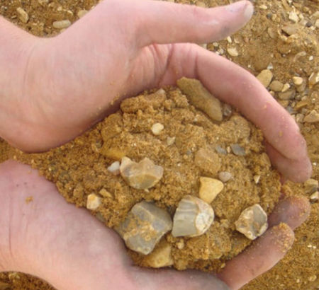 Hands cupping a mixture of sandy brown soil and small rocks
