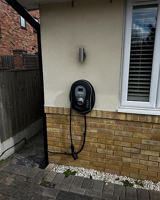 Wall-mounted electric vehicle charger with a cord, attached to a house exterior