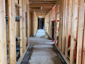 A view looking down a long corridor under construction with exposed wooden timber frames