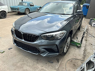 A blue BMW car with a damaged front bumper is parked