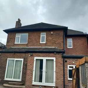 Two-story red brick house with white-framed windows and patio doors