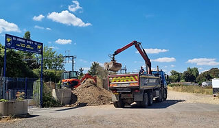 A construction site with a truck loading dirt using a crane