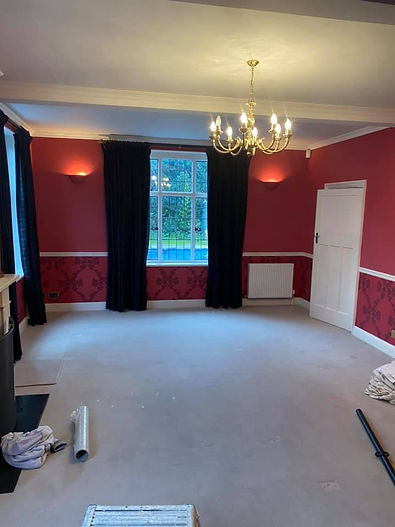 Elegant living room with red walls, dark curtains, and a lit chandelier