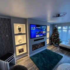 A modern living room features a central media wall with an electric fireplace and television