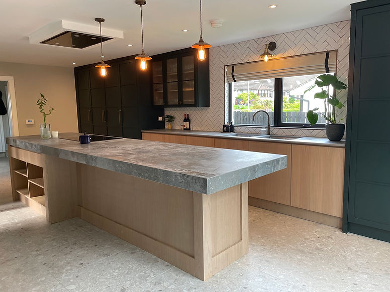 Kitchen with a large stone island, wooden cabinets, and dim pendant lights