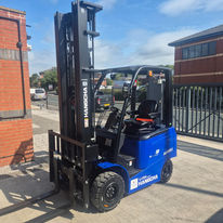 Blue Hangcha forklift parked on a sunny day near red brick buildings