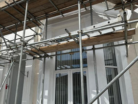 Scaffolding erected around a freshly rendered bay window during exterior renovation work