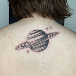 Tattoo of Saturn with its rings on a person’s upper back